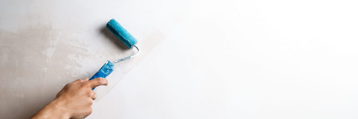 Close up photo of hand painting wall with roller in white color. Copy space.